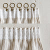Textured white curtain with gold rings and clips on a light wooden background