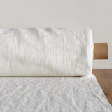 Rolled-up antique white fabric on a wooden surface with a neutral background