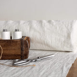 Wooden box with spools of white thread and a pair of scissors on a fabric-covered surface.
