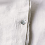 Close-up of a white shirt with a button on a light background