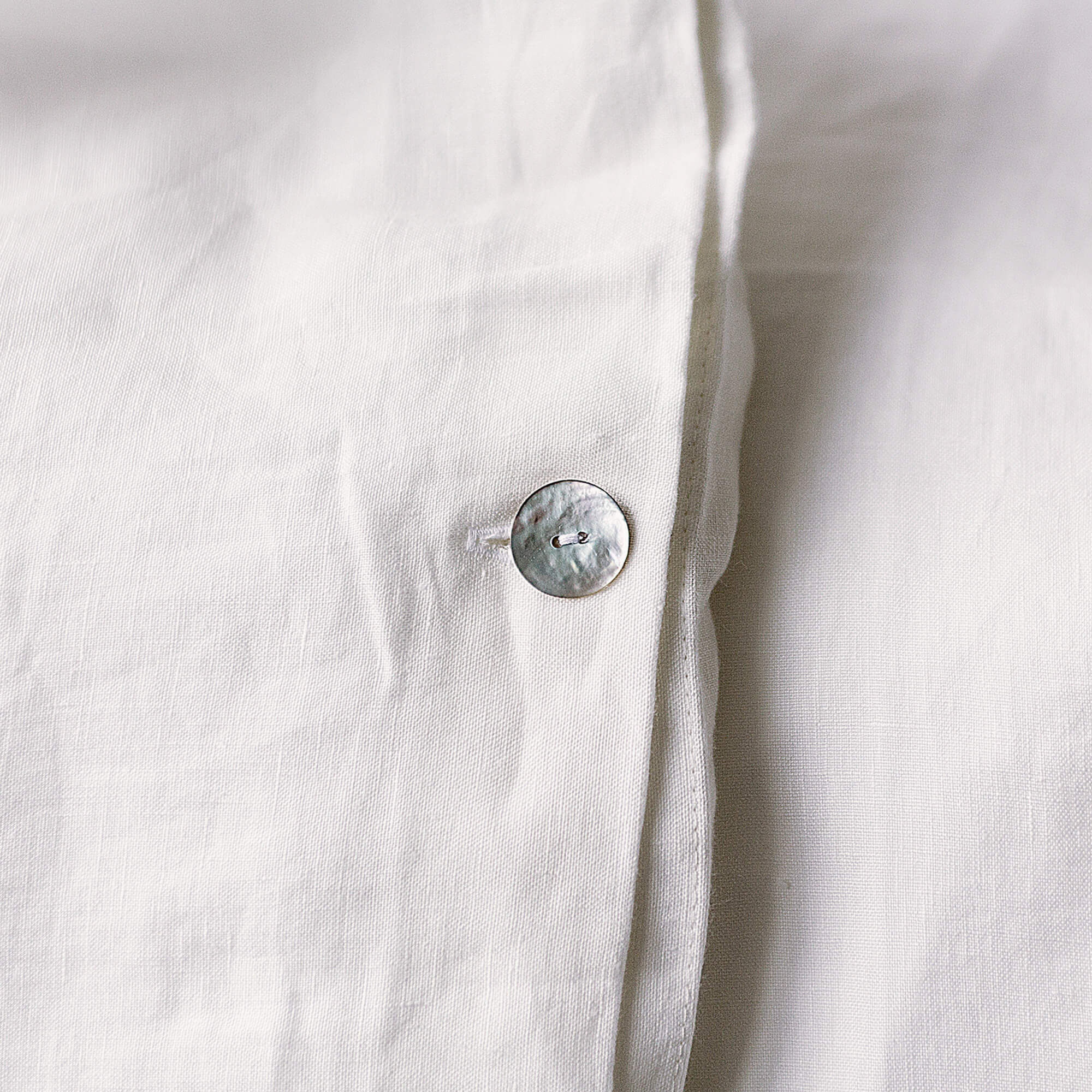 Close-up of a white shirt with a button on a light background