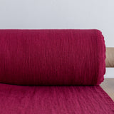 Roll of burgundy red fabric on a light gray background