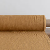 Roll of dusty mustard fabric on a light gray background