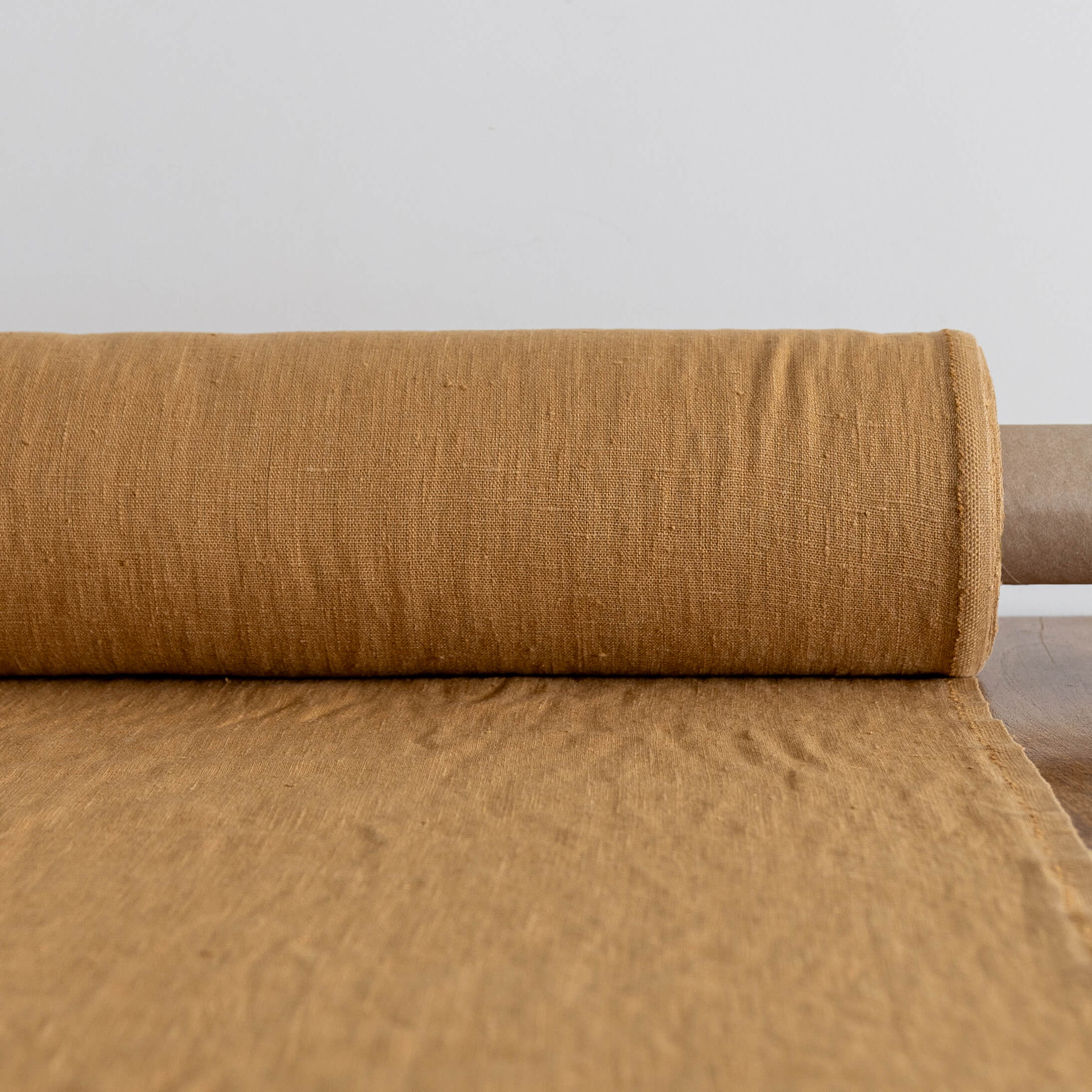 Roll of dusty mustard fabric on a light gray background