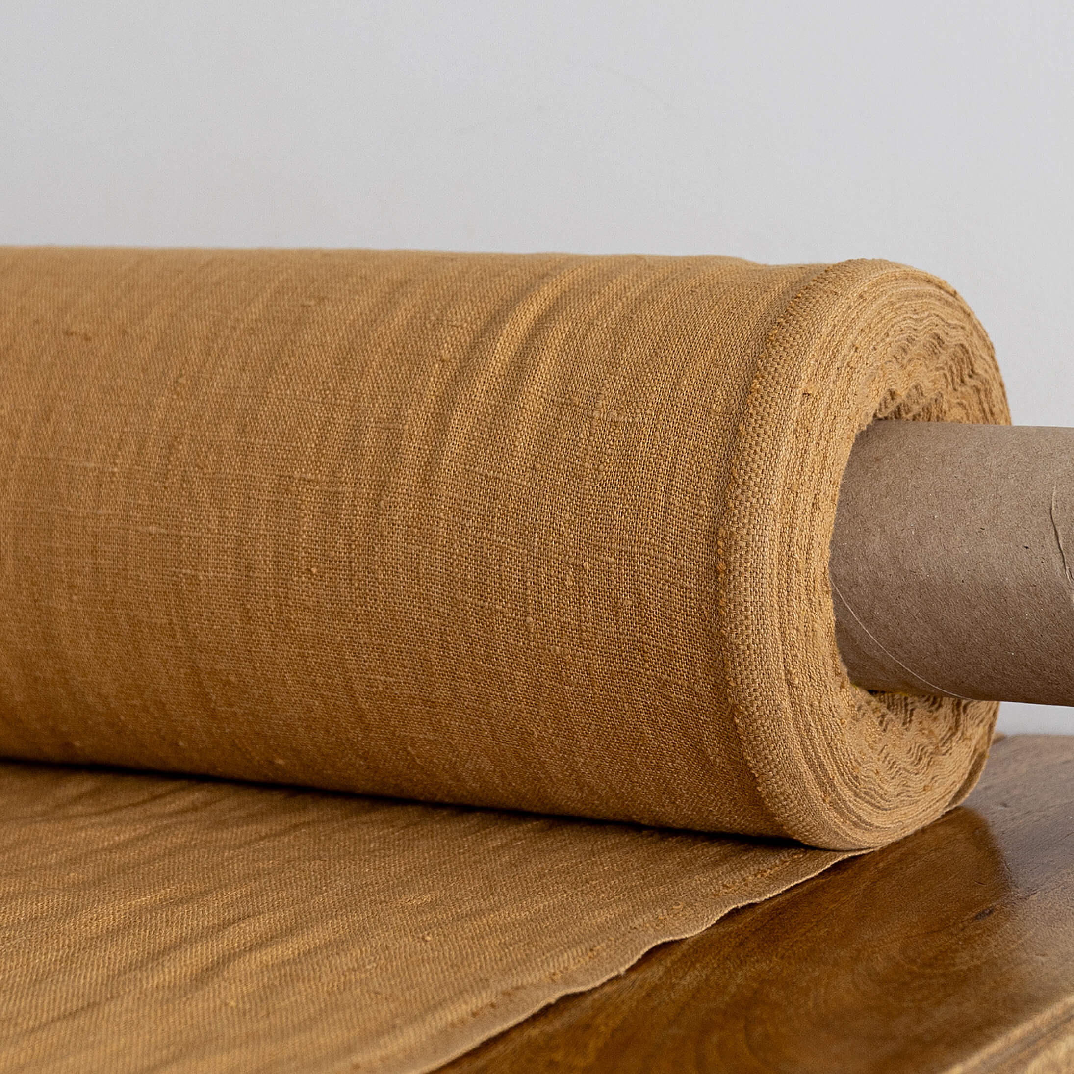 Roll of dusty mustard paper on a wooden surface with a neutral background