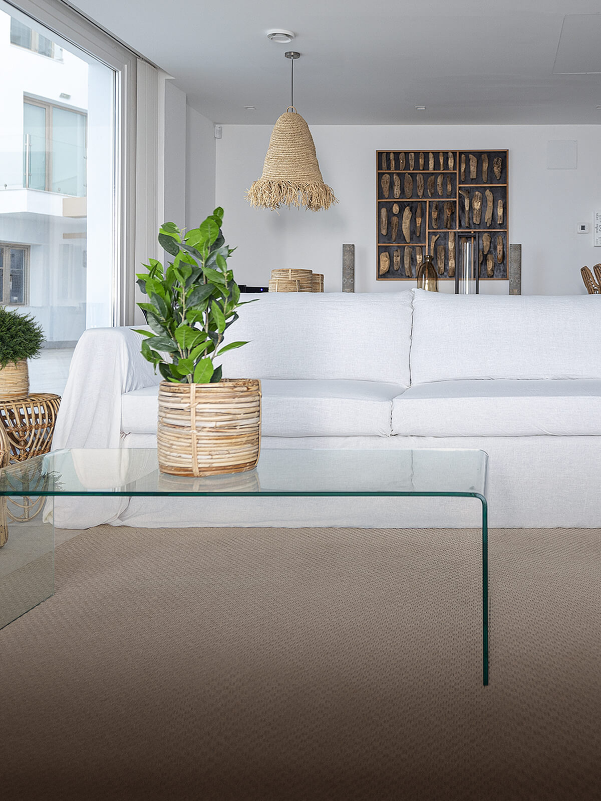 White linen couch cover on a sofa with a glass coffee table and a potted plant