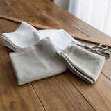 Folded fabric pieces on a wooden table with scissors and a ruler.
