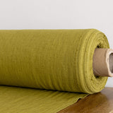 Rolled-up olive green fabric on a wooden surface with a neutral background