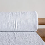 Roll of optical white fabric on a wooden surface with a neutral background