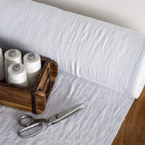 Optical white fabric on a table with spools of thread and scissors in the foreground.