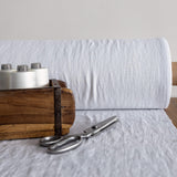 Wooden box with spools of thread and a pair of scissors on a optical white fabric background