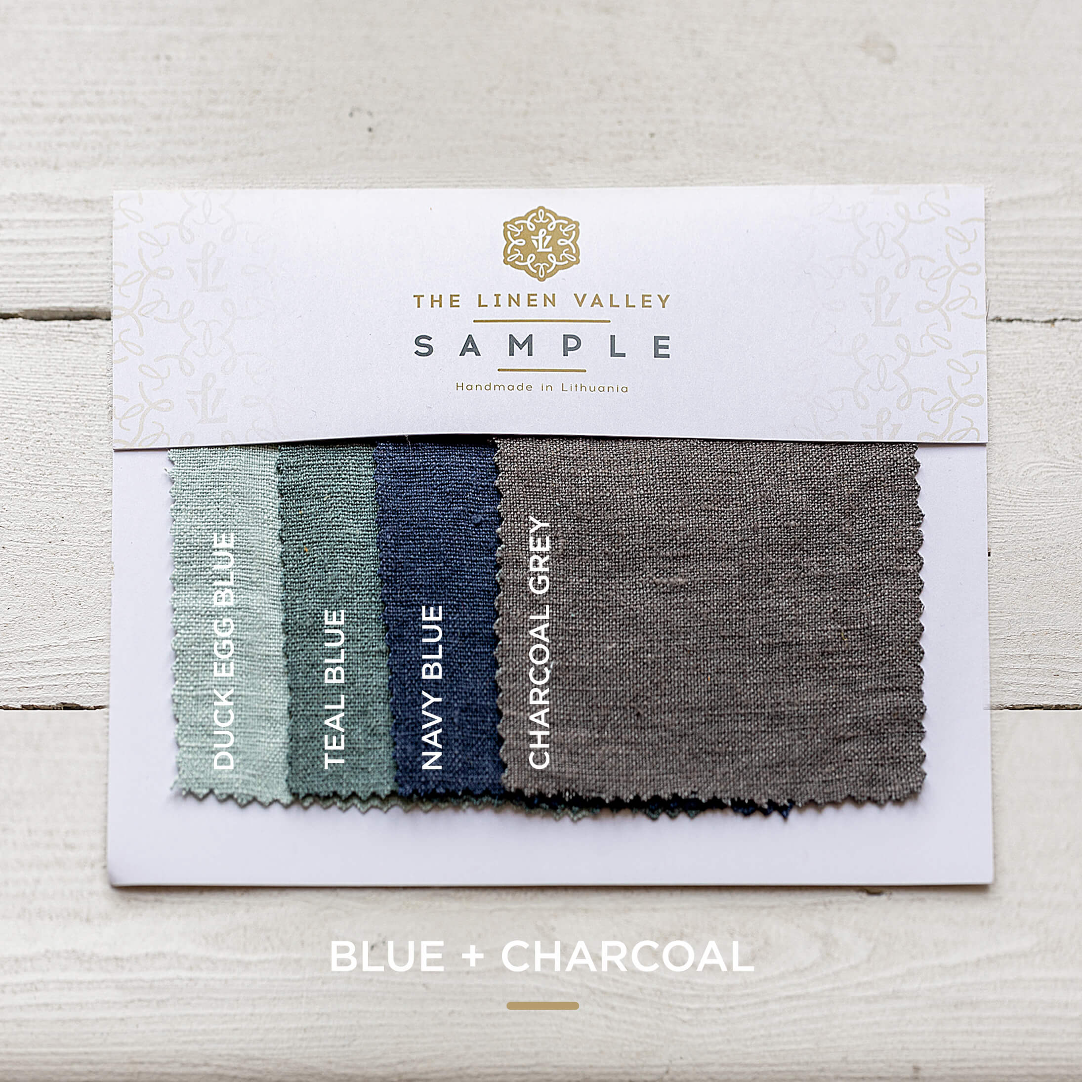 Fabric sample card with blue and charcoal gray swatches on a light wooden surface.