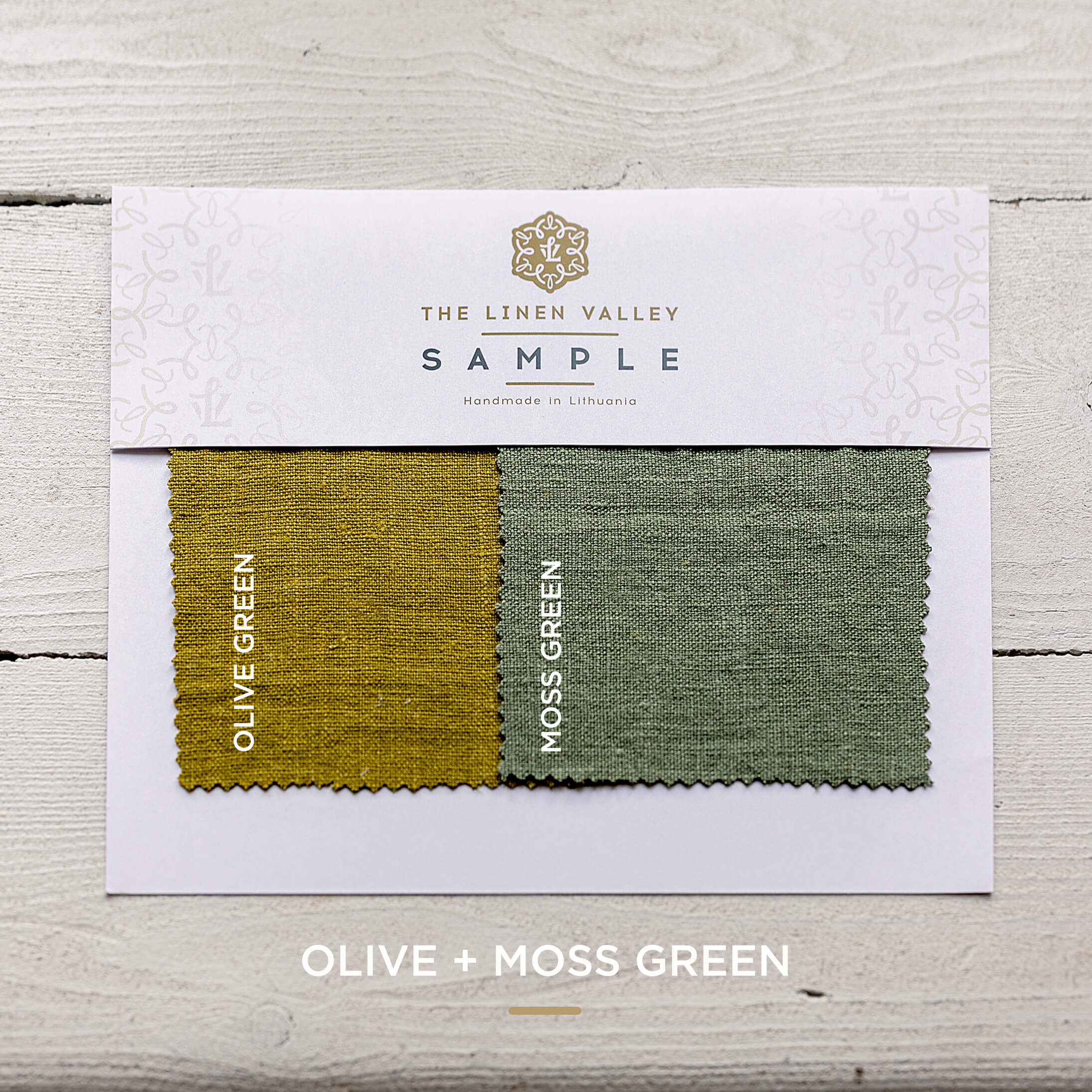 Fabric sample card with olive and moss green swatches on a wooden surface.