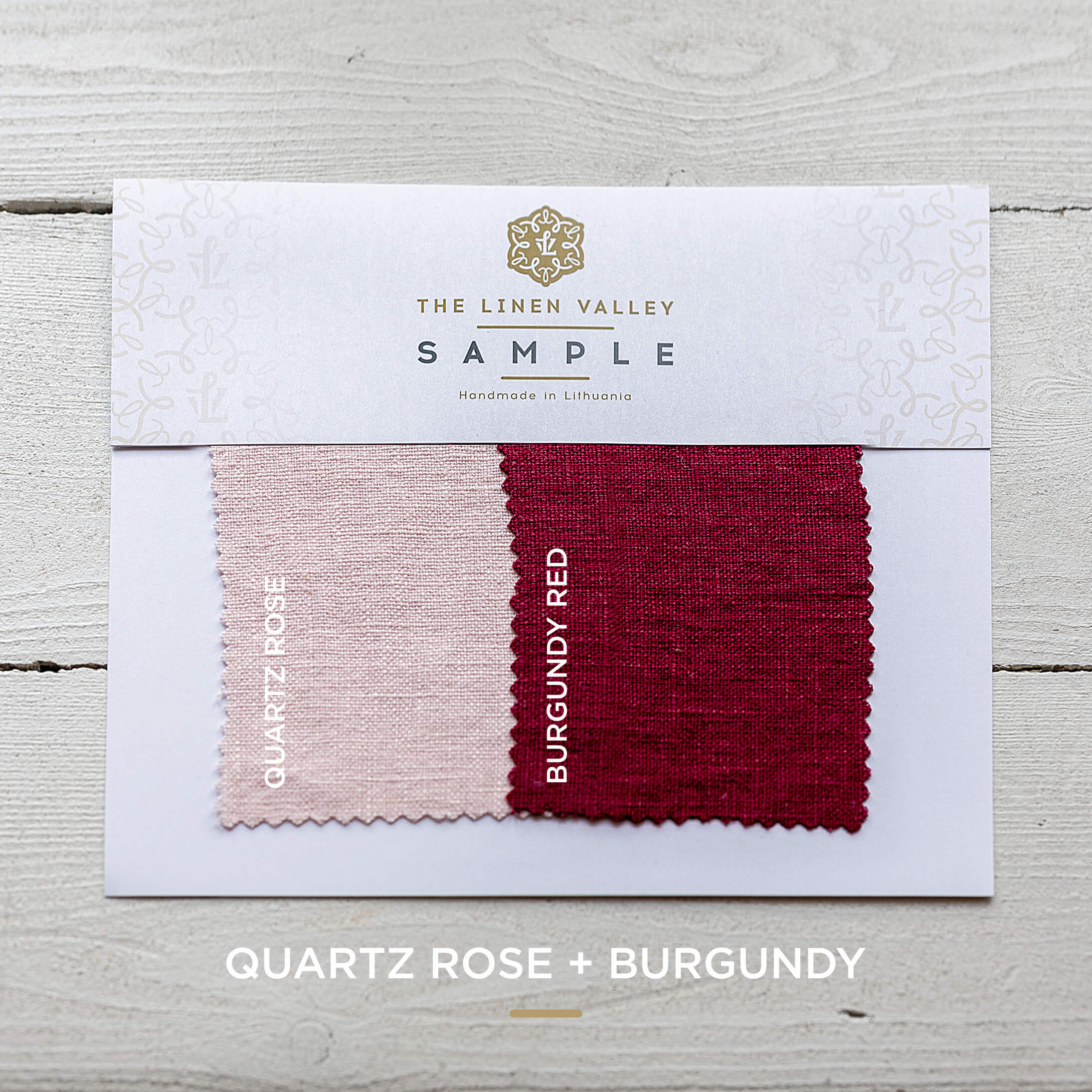 Fabric sample card with Quartz Rose and Burgundy colors on a wooden surface