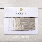Fabric swatch sample with 'The Linen Valley' branding on a wooden surface