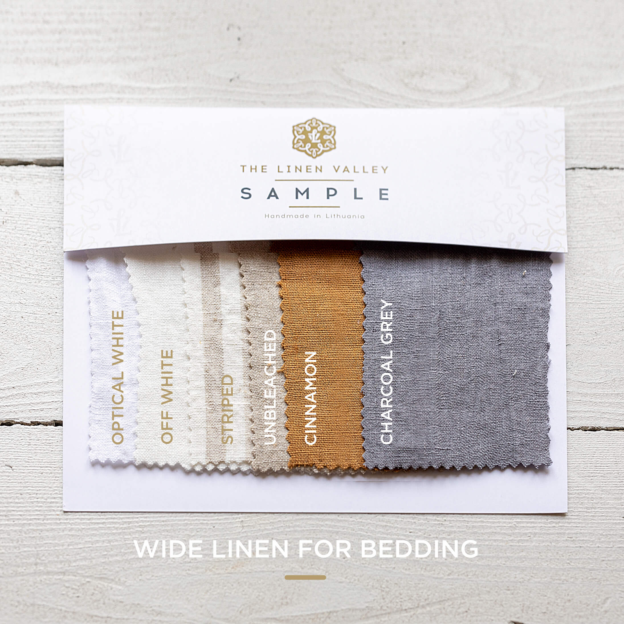 Wide Linen for Bedding Fabric swatch sample card with colors and 'The Linen Valley' branding on a light wooden surface.