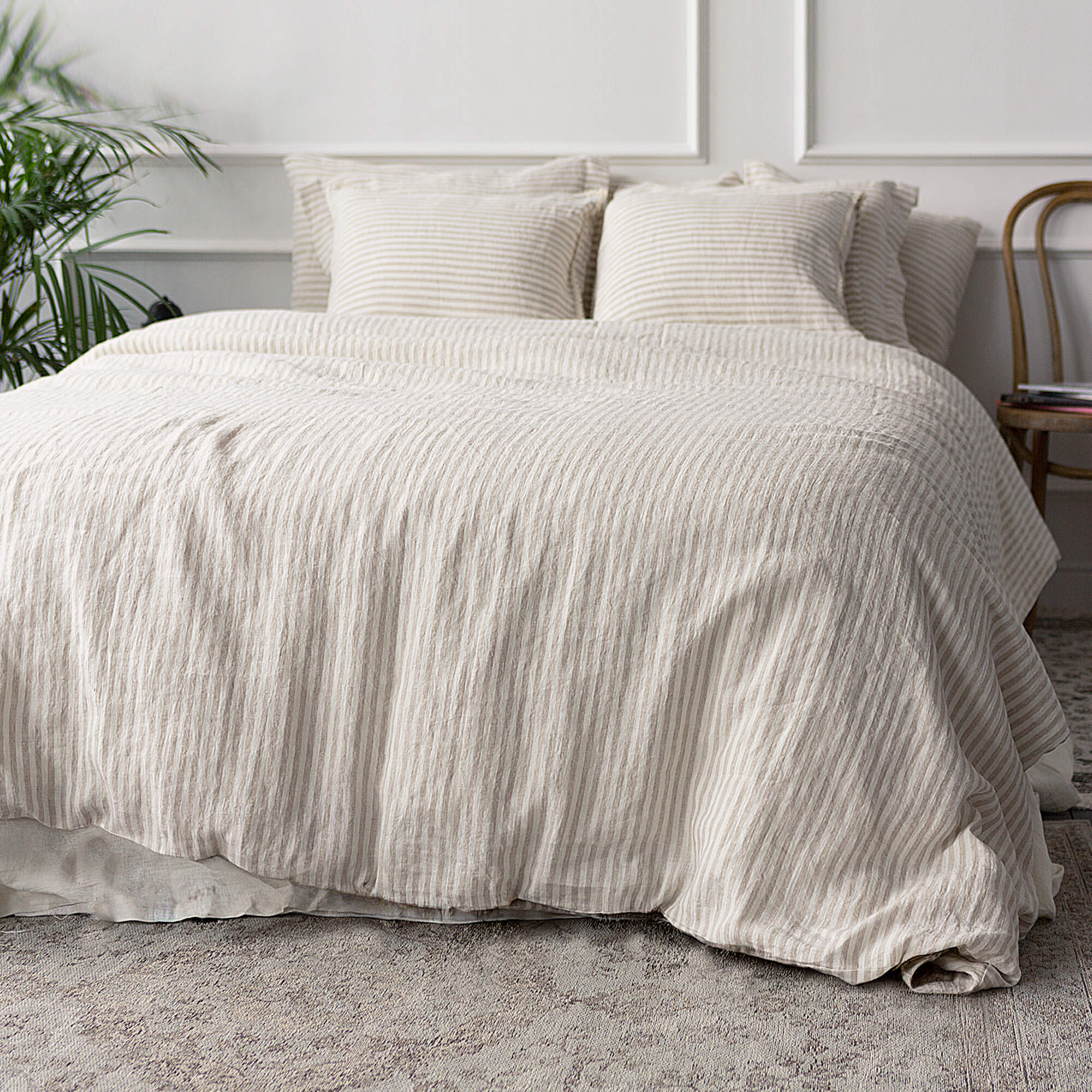 Beige textured duvet cover set on a bed in a bedroom with plants and a chair.
