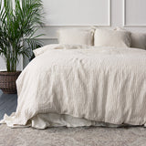 Beige striped duvet cover set on a bed with a plant in the corner.