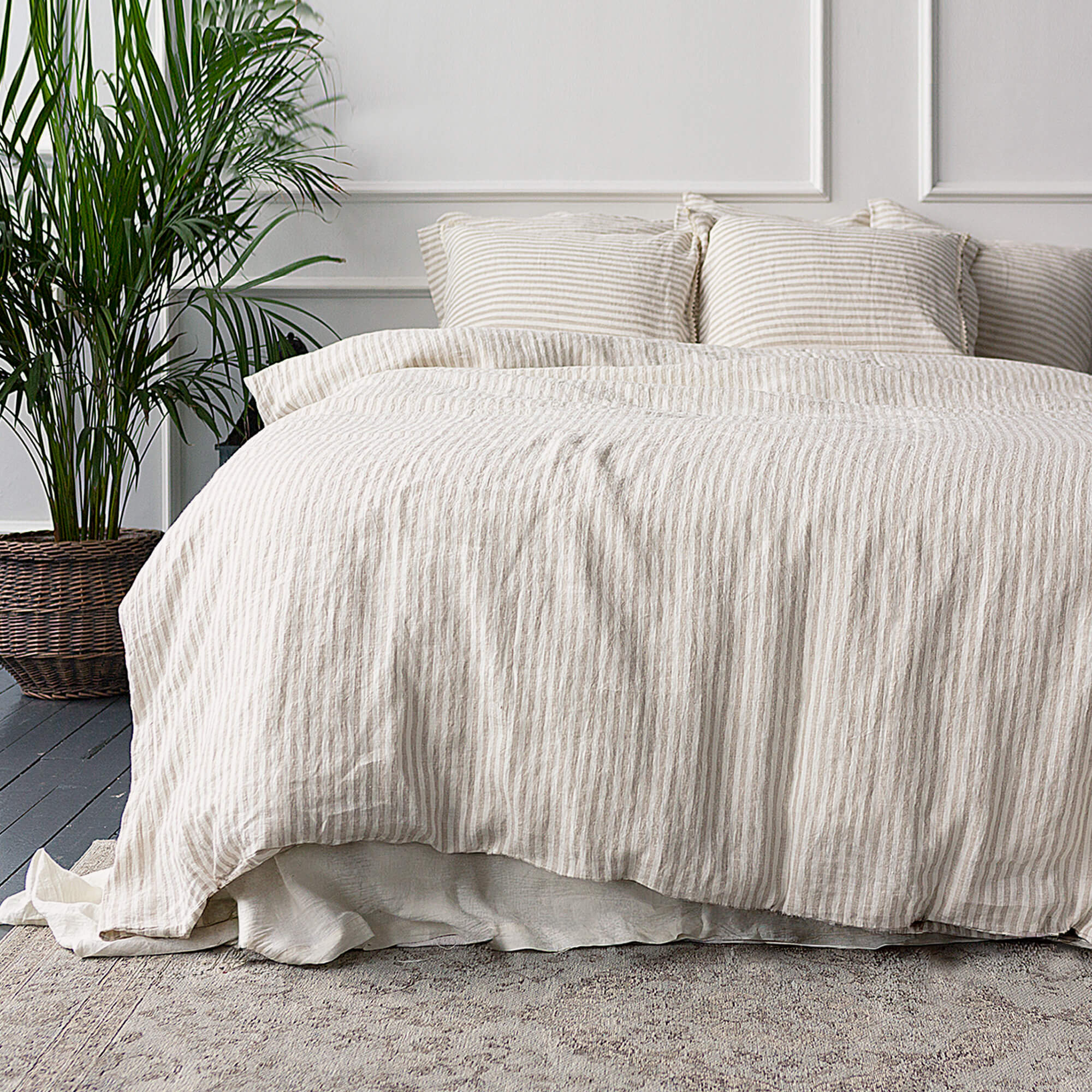 Beige striped duvet cover set on a bed with a plant in the corner.