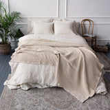 Neatly made bed with beige bedding in a bedroom setting.