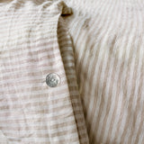 Close-up of a beige and white striped fabric with a button.
