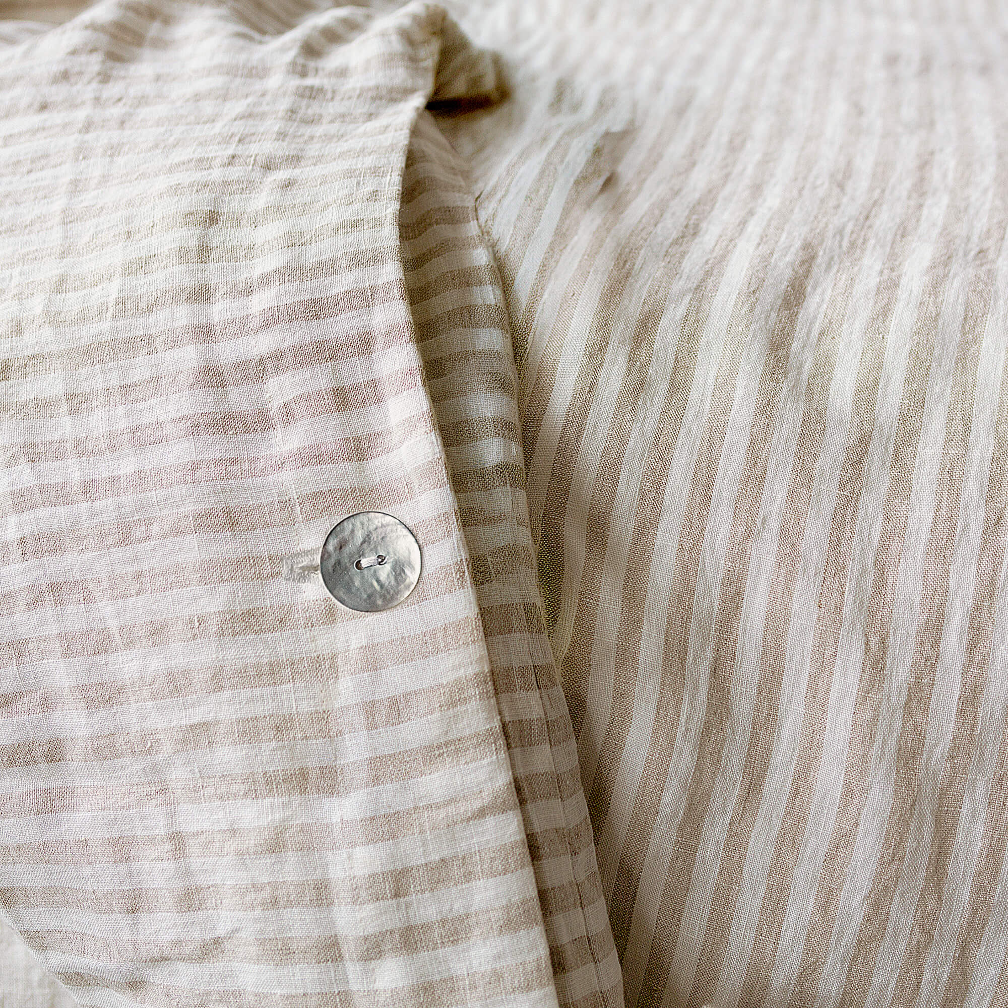 Close-up of a beige and white striped fabric with a button.