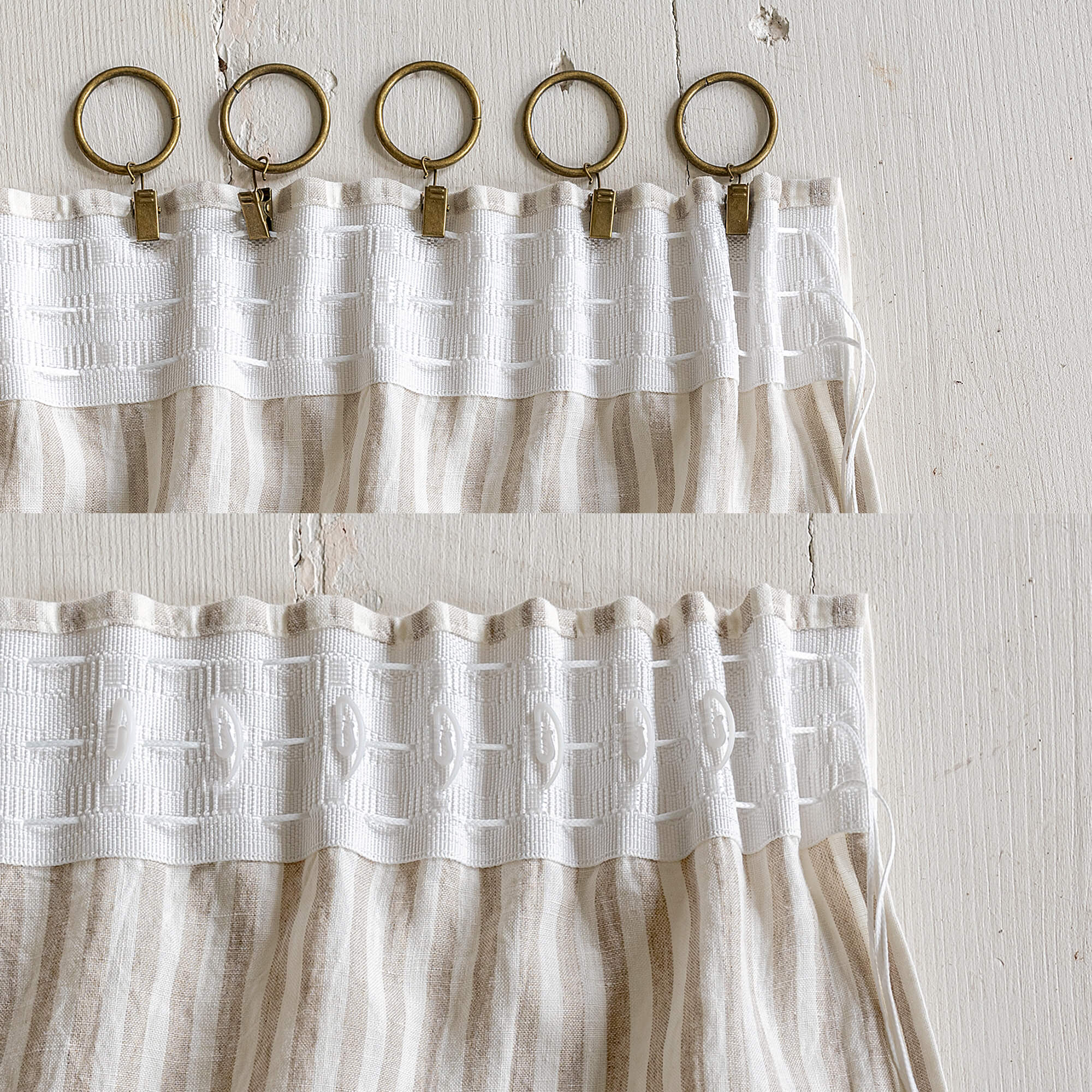 White textured curtain with gold rings and clips on a light wooden background