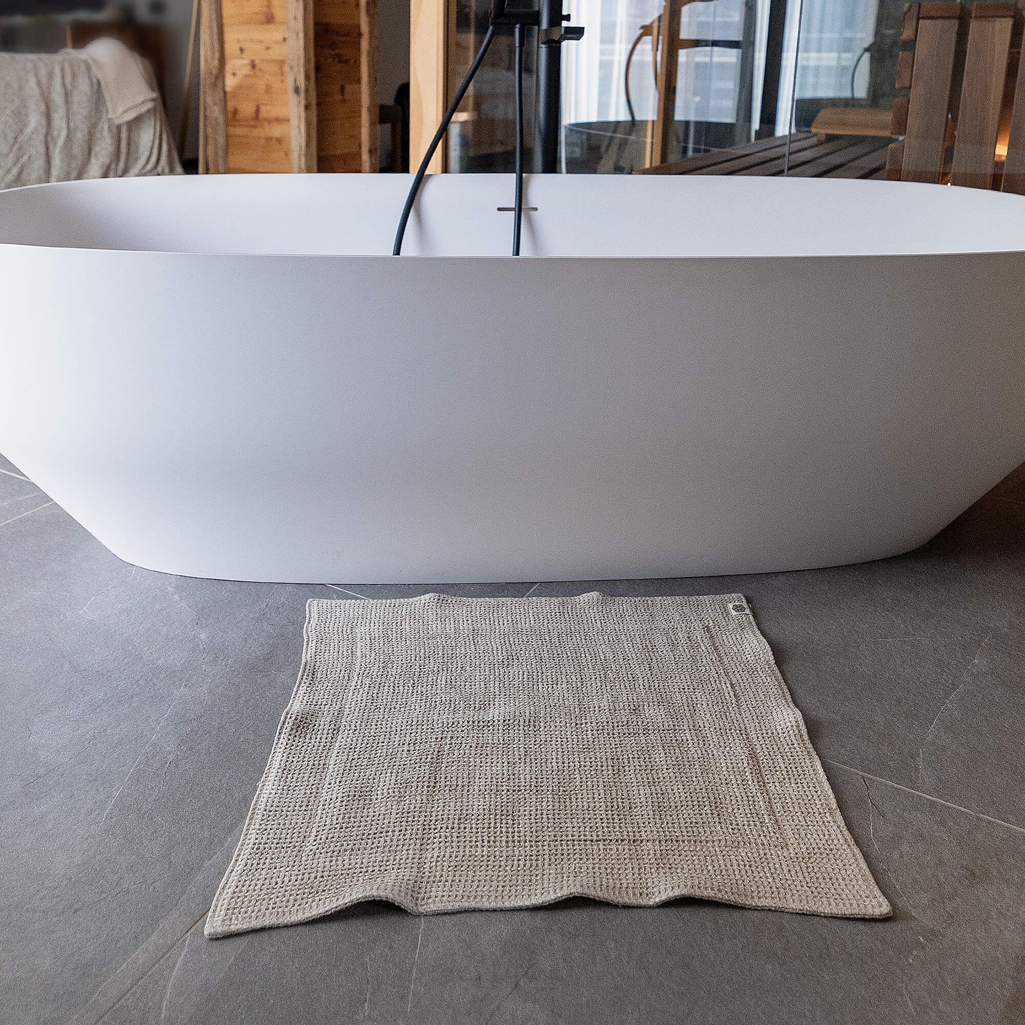 White freestanding bathtub in a bathroom with a textured rug on the floor.