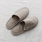 Pair of rustic natural linen slippers on white linen