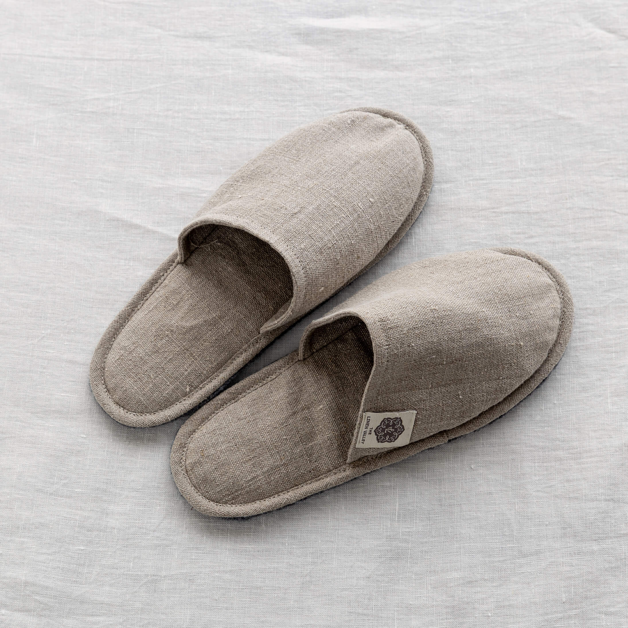 Pair of rustic natural linen slippers on white linen